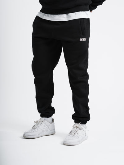 Male model wearing black One Bout Script Bottoms with white sneakers